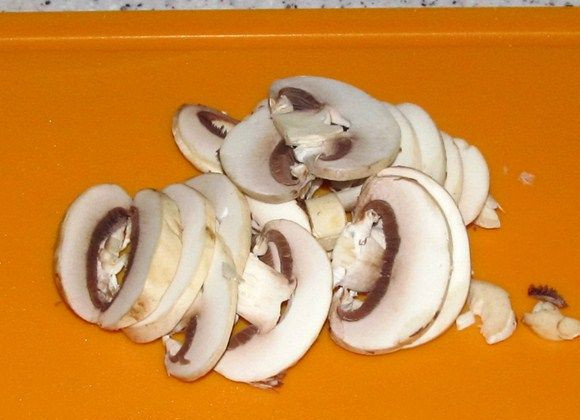 1. Этап. Макароны с грибами и сыром: 4. Тем временем вымыть, просушить и нарезать грибы. Макароны с грибами и сыром в домашних условиях можно приготовить из любых грибов (свежих или замороженных). В данном случае используются шампиньоны.