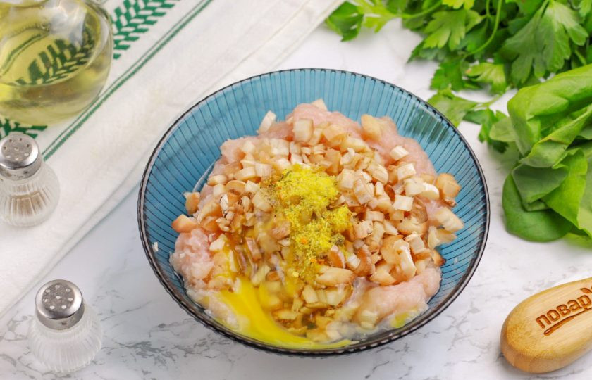 1. Этап. Шампиньоны с куриным фаршем: Нарежьте оставшиеся грибные ножки мелким кубиком и добавьте в фарш вместе с универсальной приправой. Добавьте мелкое куриное яйцо или же его половину, чтобы начинка не получилась слишком жидкой. Тщательно все перемешайте.