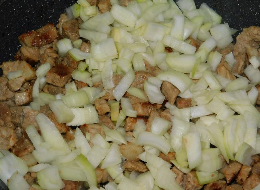 1. Этап. Свинина с маринованными огурцами, тушеная в горчичном соусе: Добавьте нарезанный лук и обжаривайте 2-3 минуты все вместе.