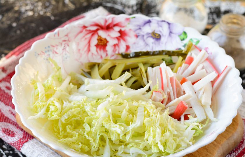 1. Этап. Крабовый салат с соленым огурцом: Переложите в миску нарезанные продукты: капусту, крабовые палочки и огурцы.