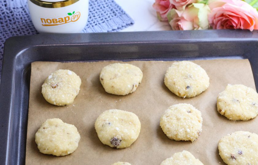 1. Этап. Медово-творожное печенье с орехами: Разделите тесто на равные части и смочите руки в воде. Скатайте каждую часть в колобок, слегка расплющите и обмакните с одной стороны в сахар. Выложите на пергаментную бумагу на противне.