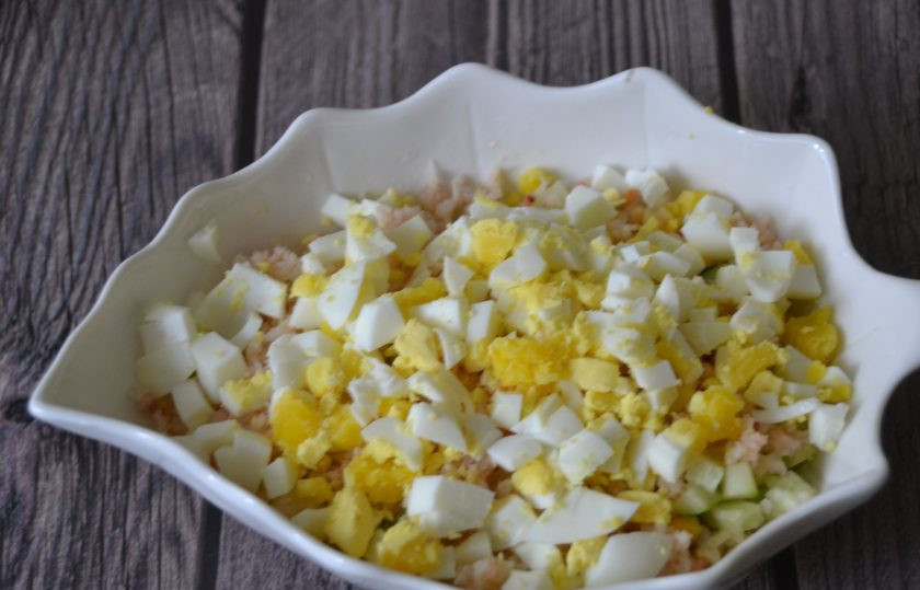 1. Этап. Салат с Дошираком: Порежьте кубиком яйца и выложите в салат.