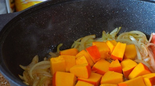 1. Этап. Говяжья голяшка в сливочно-овощном соусе: Выложить лук в казан и обжарить, 5 минут, огонь средний. Добавить тыкву, жарить ещё 5 минут.