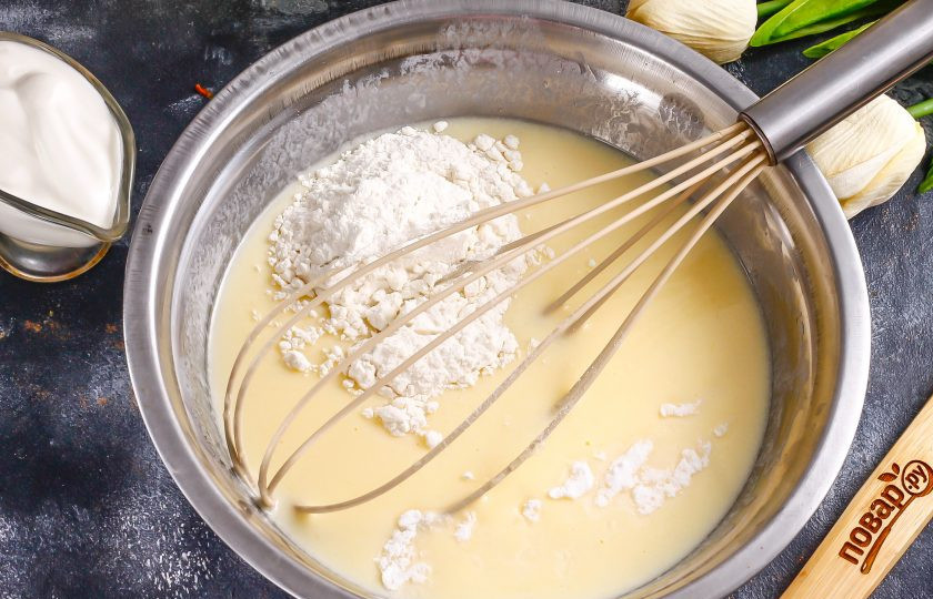 1. Этап. Торт из оладий: Всыпьте муку и разрыхлитель. Аккуратно вмешайте сухие ингредиенты в жидкую массу, но не взбивайте. Тесто должно получиться очень густым, плотным, как густая сметана.