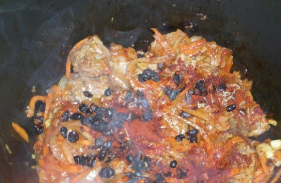 1. Этап. Плов из перловки с мясом: В казан наливаем масло и хорошенько его нагреваем. Выкладываем нарезанное мясо и жарим до румяной корочки, затем добавляем лук и продолжаем жарить. Когда лук станет золотистого цвета, добавляем морковь и жарим ее до мягкости. Теперь добавляем зиру и томатную пасту, перемешиваем все, жарим пару минут. Потом всыпаем паприку и барбарис, кладем в казан острый перчик и очищенную от шелухи головку чеснока.