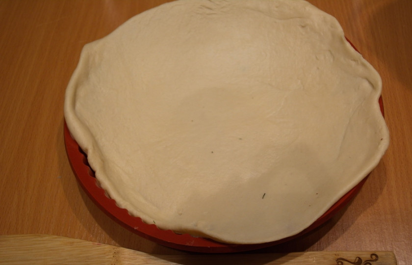 1. Этап. Пирог с сыром из дрожжевого теста: Полученное тесто разделите на 2 части. Ту, что крупнее, раскатайте, выложите ею дно формы (с бортиками).