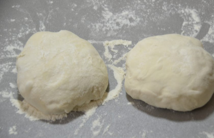 1. Этап. Пицца по-немецки: Готовое тесто разделите на две части и подкатайте в шар.