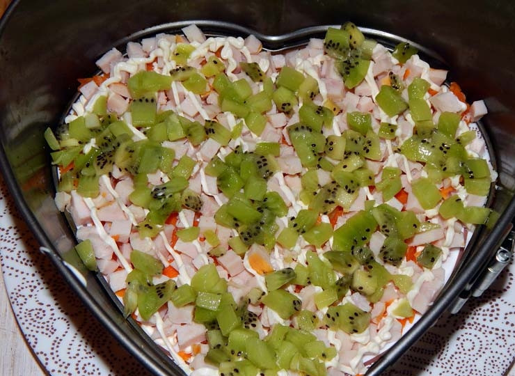 1. Этап. Салат с киви и ветчиной: Одно киви порежьте мелким кубиком и выложите на блюдо после ветчины, смажьте майонезом.