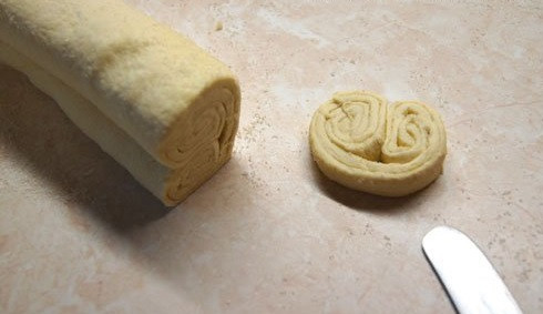 1. Этап. Берлинское печенье: 3. Снова присыпьте сахаром. Затем сверните тесто, заворачивая края в середину. Плотно прижмите получившийся рулет руками и острым ножом нарежьте на небольшие кусочки.