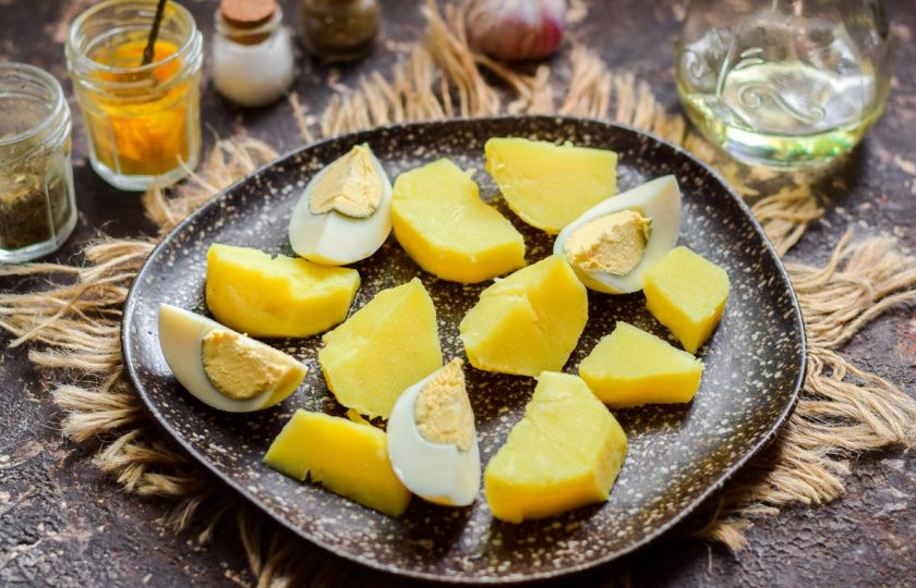 1. Этап. Салат из копченой рыбы с луком: Куриное яйцо отварите и почистите, нарежьте на 4 дольки и выложите рядом с картофелем.