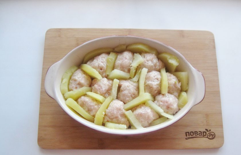 1. Этап. Запеканка с тефтелями: Из фарша сформируйте тефтели, выложите в форму. Картофель выложите между тефтелями и по периметру формы.