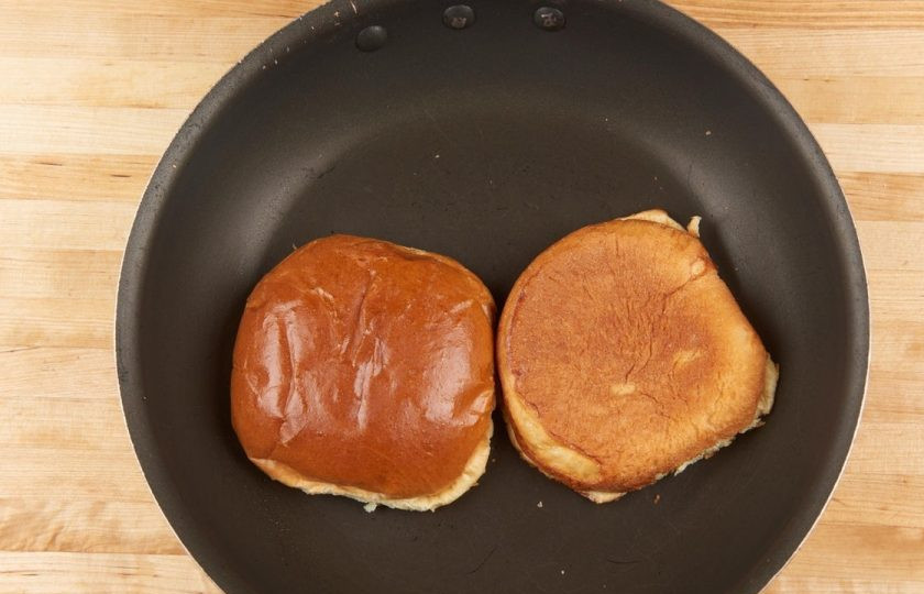 1. Этап. Умами бургер: 4. Тем временем на сковороде разогрейте масло. Обжарьте в нём булочки, разрезав их пополам. С каждой стороны по 1,5 минуты.