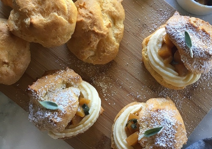 1. Этап. Бри с персиком: 7. Остывшие профитроли разрежьте напополам. Одну половину наполните персиком и сливочным сыром с помощью кондитерского шприца. Второй половинкой накройте десерт и посыпьте сахарной пудрой.