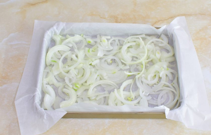 1. Этап. Судак с лимоном в духовке: Противень для запекания застелите пергаментом и смажьте растительным маслом. Лук очистите, нарежьте полукольцами и разложите по противню.