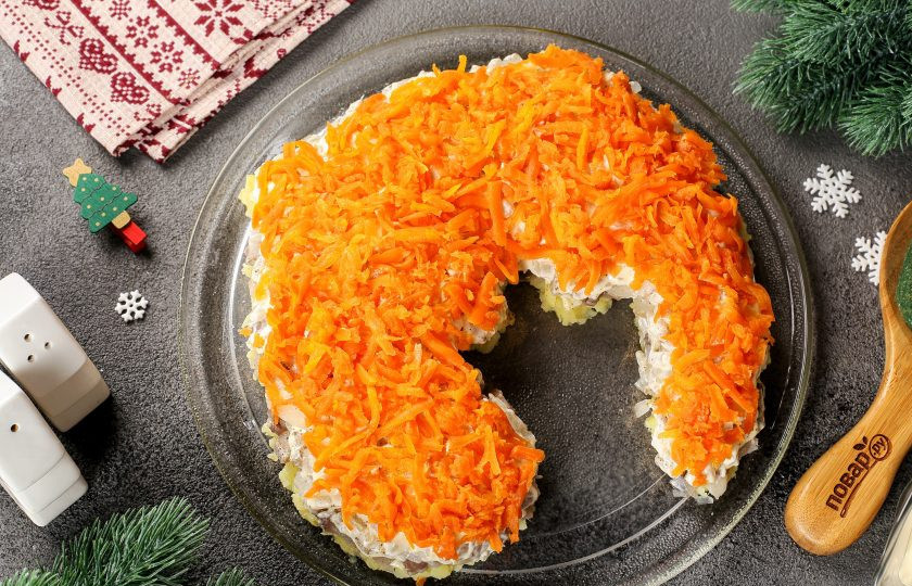 1. Этап. Селедка под шубой на год Дракона: На лук выложите тертую на крупной терке морковь. Посолите и смажьте майонезом.