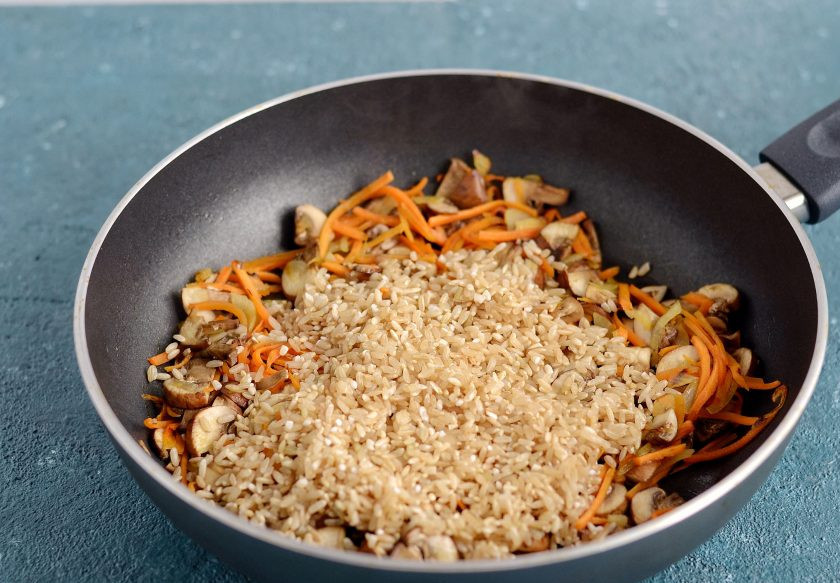 1. Этап. Бурый рис с грибами: Добавьте промытый рис, специи и соль, ещё раз перемешайте.