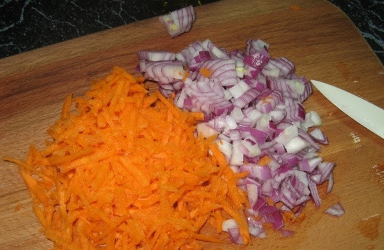 1. Этап. Плов с морепродуктами: Морковь трем на крупной терке, а лук нарезаем небольшими кубиками. В кастрюле с толстыми стенками разогреваем оливковое масло и обжариваем на нем овощи до золотистого цвета.