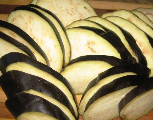 1. Этап. Свинина, запеченная с баклажанами в духовке: Баклажаны режем кружочками и обжариваем на растительном масле с двух сторон, до мягкости. Не забудьте посолить! Чеснок пропустите через пресс, обмажьте им баклажаны.