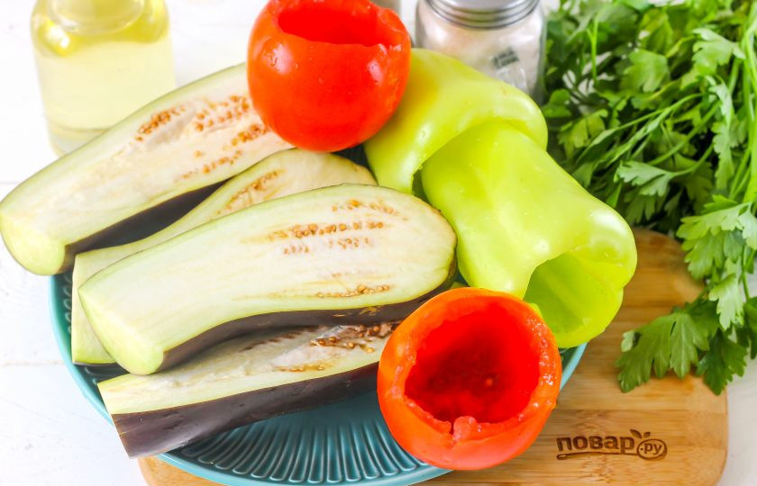 1. Этап. Бадымджан: Промойте овощи в воде. С баклажанов срежьте хвостики и разрежьте их пополам. Перцы очистите от семян и промойте. Из помидоров вырежьте зеленые сердцевинки и удалите мякоть, оставляя овощи полыми.