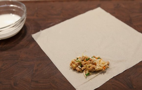 1. Этап. Мясо в рисовой бумаге: 6. На рабочий стол положите листик рисовой бумаги. На край выложите ложку начинки.