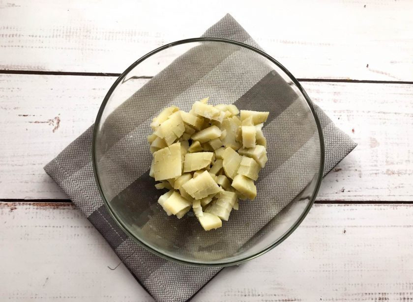 1. Этап. Оливье с печенью: Вареный картофель очистите от кожуры, нарежьте небольшими кубиками и выложите в глубокую тарелку.