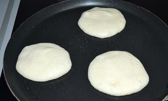 1. Этап. Вкусные оладушки: Разогрейте и смажьте небольшим количеством масла сковороду с антипригарным покрытием, налейте столовой ложкой тесто.