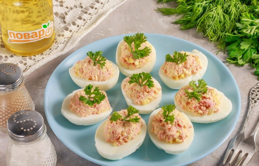 1. Этап. Яйца фаршированные вареной колбасой: Украсьте блюдо свежей зеленью и подайте к столу. Можно приготовить закуску заранее, за 1-2 часа до прихода гостей, и хранить в холодильнике.