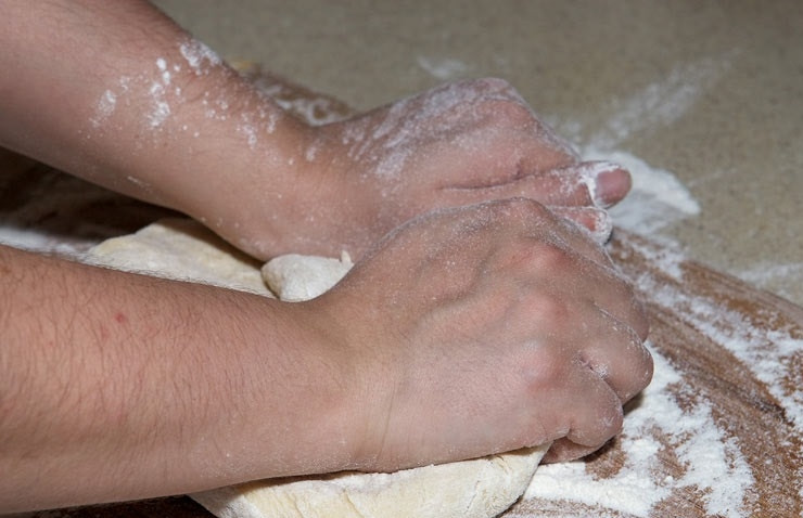 1. Этап. Заварное тесто для чебуреков с водкой: 6. Когда ложкой управляться уже сложно, переложите тесто на присыпанную мукой поверхность и продолжайте вымешивать руками. Делайте это тщательно, чтобы оно получилось нежным.