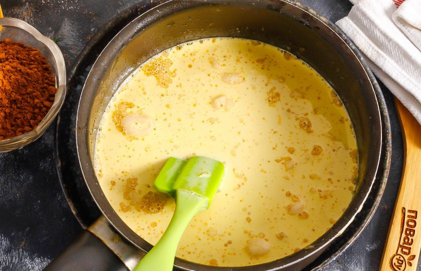 1. Этап. Шоколадный медовик: Выложите в ковш сливочное масло, мед, влейте яичную массу, слегка прогрейте, непрерывно помешивая, и добавьте соду. Масса покроется пеной. Перемешайте и снимите емкость с огня.