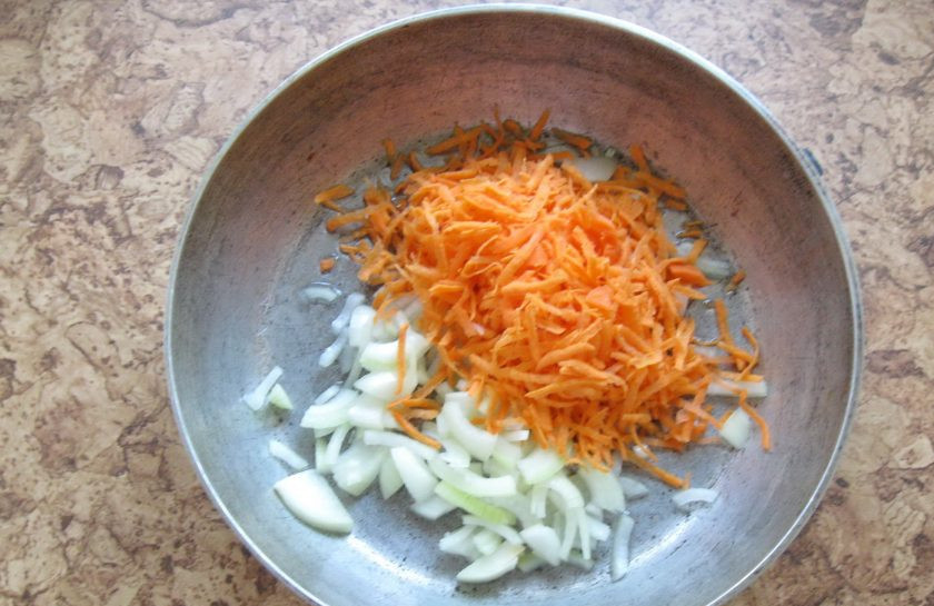 1. Этап. Баклажанная икра жареная: Одну крупную луковицу и морковь очистите, помойте. Лук нарежьте произвольно, а морковь натрите на терке. Выложите в сковороду.