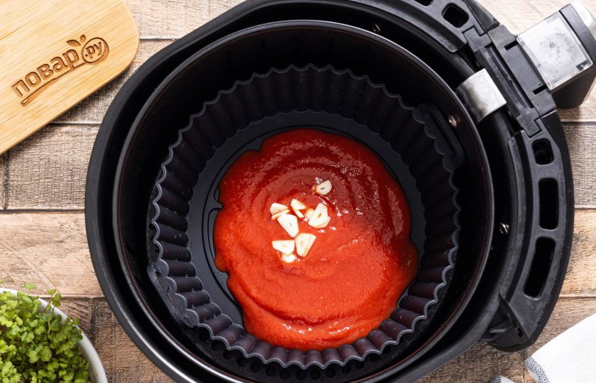 1. Этап. Макароны в аэрогриле: Выложите в форму для запекания нарезанный пластинами зубчик чеснок и протертые томаты. Я использую силиконовую форму, которую можно вставить в аэрогриль, но можно готовить сразу в чаше аэрогриля для большой порции.