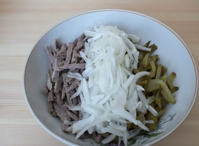 1. Этап. Салат Шахтерский с солеными огурцами: Огурцы нарежьте соломкой, добавьте к говядине. Сверху положите лук.