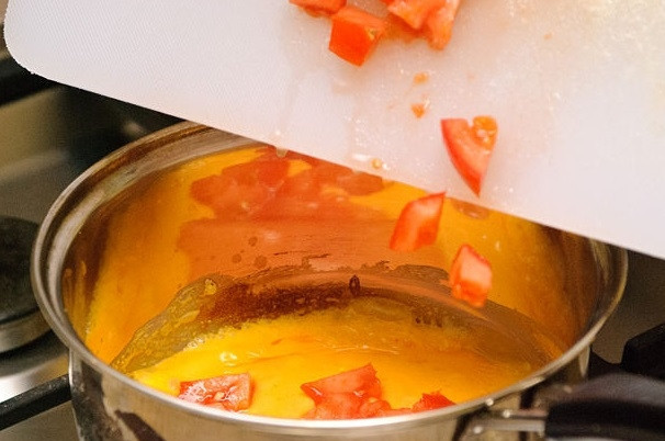 1. Этап. Острый сырный соус: 3. Помидор промойте, мелко нарежьте и добавьте в сотейник.