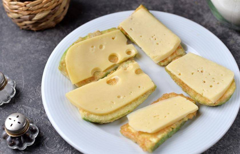 1. Этап. Сэндвичи из кабачков с сыром: Разделите кабачок на две одинаковые по количеству части. На половину кабачков выложите по тонкому ломтю твердого сыра, который хорошо плавится при высокой температуре.