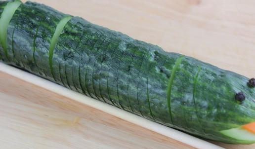 1. Этап. Новогодний салат Символ года: Украсить салат символом года - змейкой. Второй огурец положить на две палочки для суши и надрезать не прорезая огурец, вырезать мордочку змейки, вставить язычок из морковки или кожицы помидора.