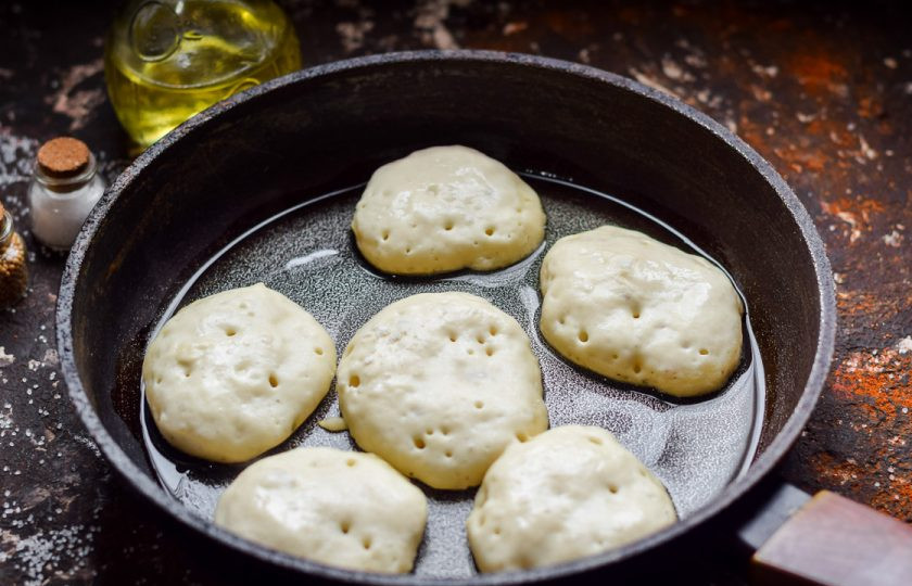 1. Этап. Оладьи без кефира и яиц: Прогрейте сковороду, влейте масло и выложите тесто столовой ложкой.