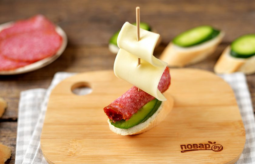 1. Этап. Канапе Кораблик: Вставьте шпажку в ломтик хлеба с огурцом. При желании из морковки можно вырезать флажки и прицепить вверху мачты.