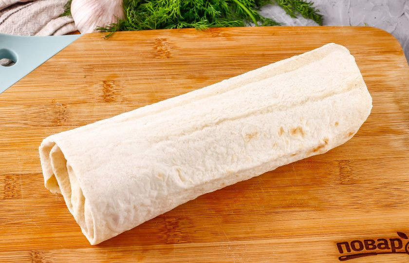 1. Этап. Азербайджанская шаурма: Аккуратно сверните край лаваша и его боковые края, заверните его рулетом, не сильно прижимая начинку, чтобы не порвать тесто. По желанию таким же образом сделайте еще одну заготовку, если готовите на двух человек.
