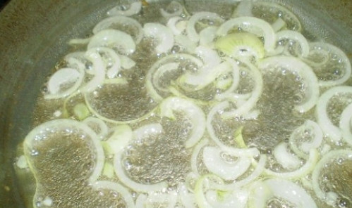 1. Этап. Печень утиная: 1. Очистите от шелухи лук. Затем нарежьте его полукольцами, смочив лезвие ножа холодной водой. Влейте в сковородку растительное масло. Разогрейте и выложите полукольца лука для обжарки до полуготовности.