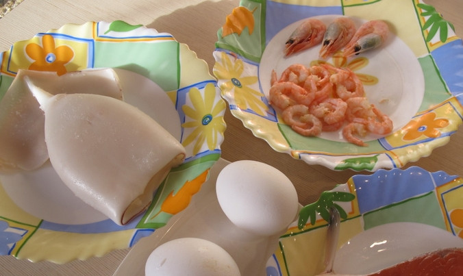 1. Этап. Салат Коктейль с морепродуктами: Очищенного кальмара промываем, а затем отвариваем в кипящей воде 2-3 минуты. Креветки также варим несколько минут, затем очищаем. Яйца варим вкрутую. Рыбку очищаем от кожи и нарезаем кусочками.