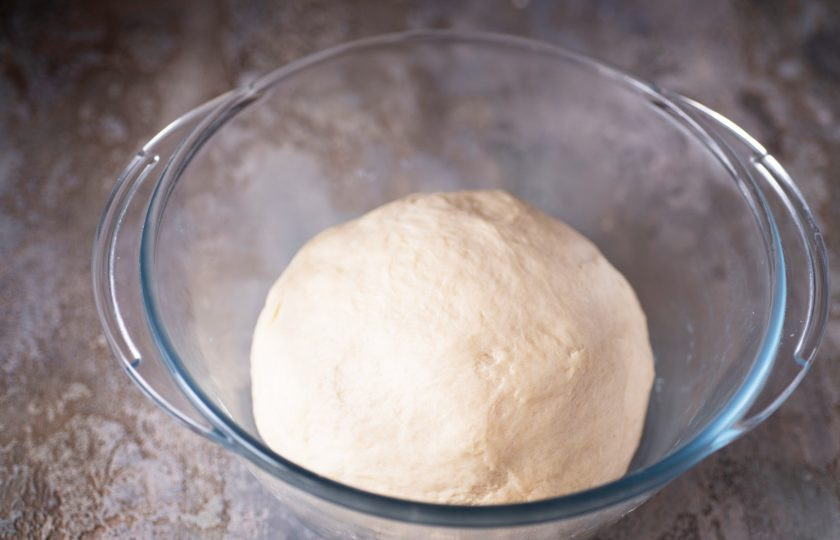 1. Этап. Корейские пончики: При этом по ходу добавления замешивайте тесто сначала ложкой, а затем руками. Муки может понадобиться больше или меньше, но тесто в итоге должно получиться мягкое, к рукам не прилипает. Готовое тесто округлите в миске. Миску с тестом накройте кухонным полотенцем и оставьте тесто в покое на один час.