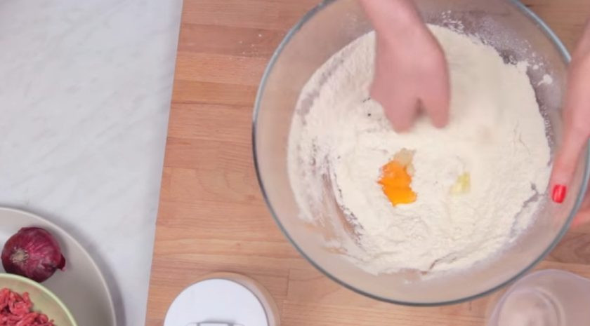 1. Этап. Пельмешки фри: 1. Приготовьте тесто: в муку добавьте соль, яйцо и небольшими порциями добавьте воду. Постепенно замесите тугое и эластичное тесто, чтобы оно не прилипало к рукам. Поместите тесто в миску и накройте его полотенцем на 20 минут.