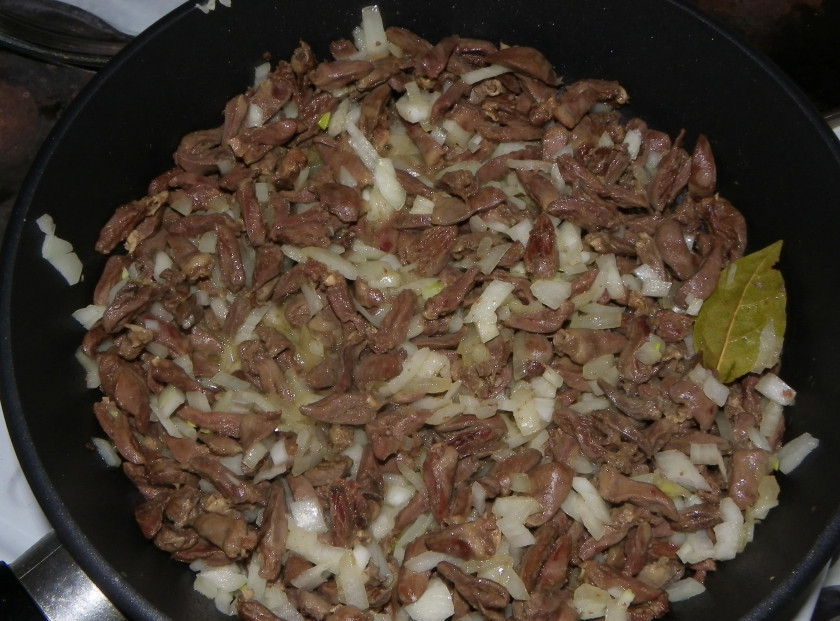 1. Этап. Жареные сердечки: 4. За время обжаривания сердечек очищаю и мою лук, нарезаю его мелким кубиком и отправляю на сковороду, добавляю лавровый лист, перемешиваю.