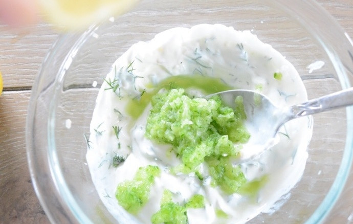 1. Этап. Картофельный салат с соусом Тцатцики: 11. Натрите на терке половинку огурца, выложите в миску к йогурту, добавьте сок половинки лимона, соль и перец по вкусу, перемешайте.