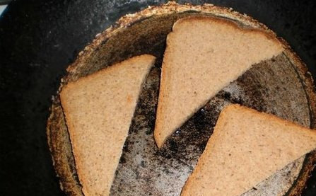 1. Этап. Гренки со шпротами: Обжариваем кусочки хлеба на сковороде с двух сторон до образования румяной корочки и сразу же натираем зубчиком чеснока обе стороны.