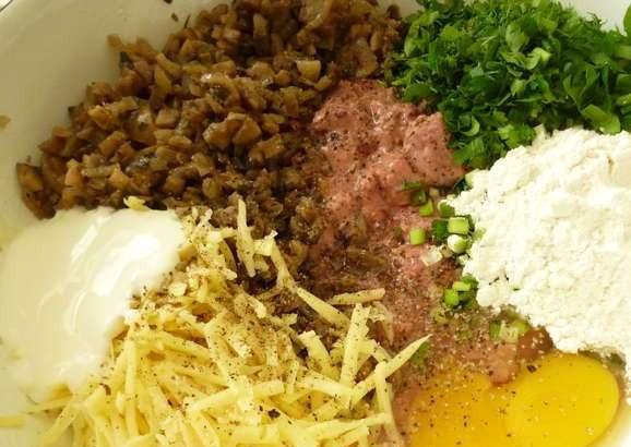 1. Этап. Печеночные котлеты с грибами: Остывшую куриную печень нарежьте кусочками. К ней добавьте нарезанную зелень, муку, сметану, муку, яйца, грибы с луком, натёртый сыр, перец и соль. Всё перемешайте и уберите в холодильник на 35 минут.