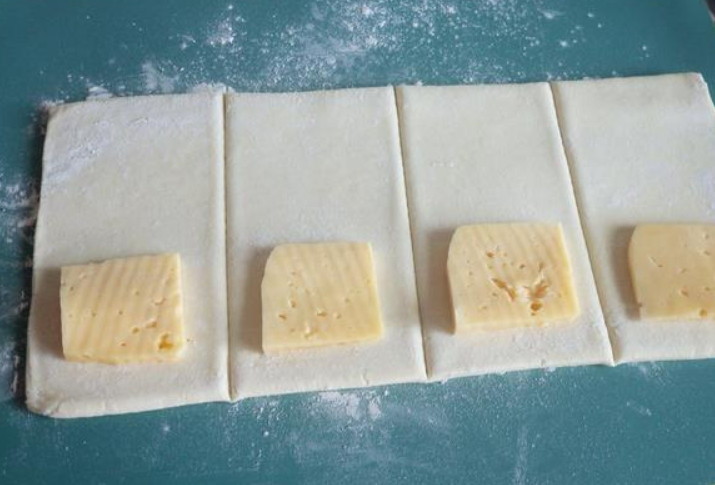 1. Этап. Слойки из готового дрожжевого теста: На каждый квадратик выкладываем по ломтику сыра.