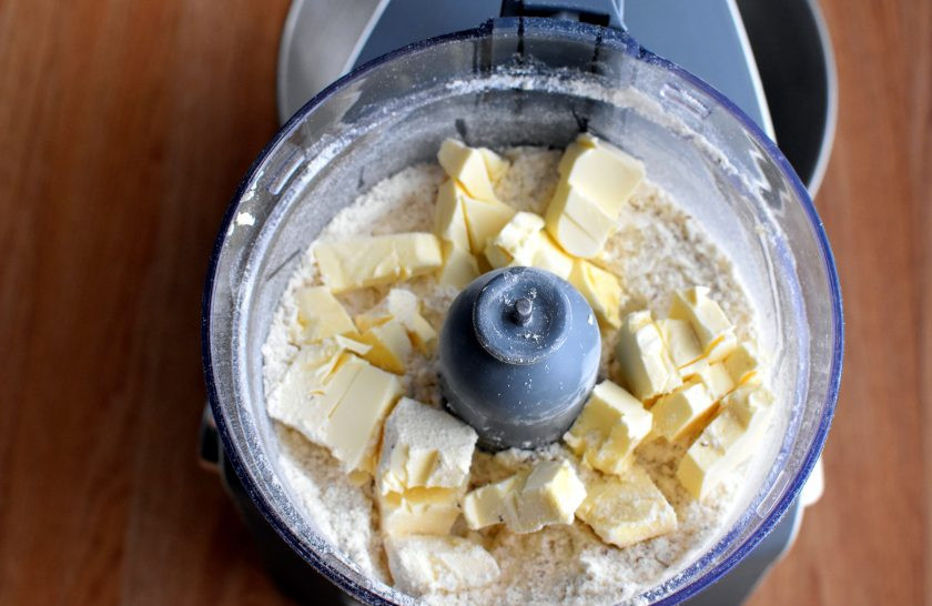 1. Этап. Песочный пирог с орехами: Добавьте холодное масло, нарезанное кусочками. Пробейте в крупную крошку в пульсовом режиме.