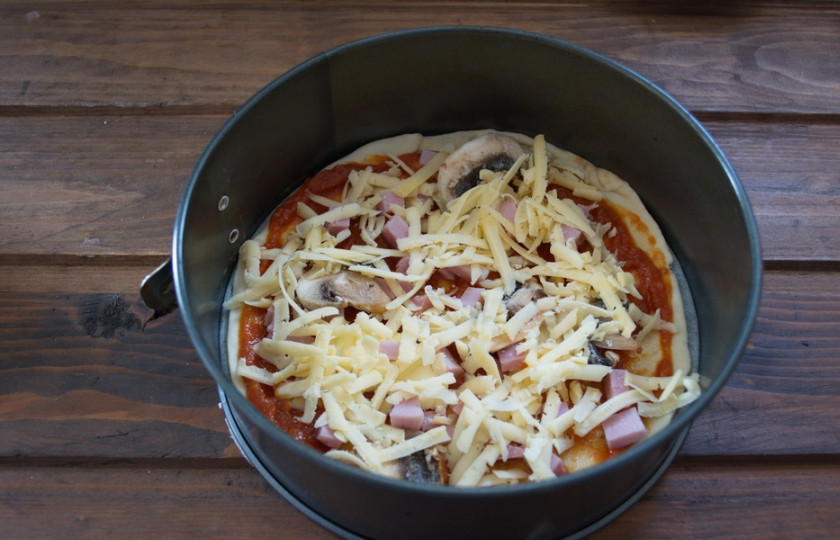 1. Этап. Пицца с шампиньонами, колбасой и сыром: Натрите на крупной терке сыр. Выложите поверх всей начинки. Не следует использовать терку с мелкими делениями. Сыр в процессе запекания подсохнет и пицца будет сухой. Посыпьте пиццу специями и солью. Разогрейте духовку до 200 градусов.