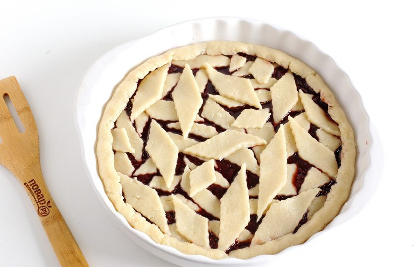 1. Этап. Песочный пирог: Достаньте вторую часть теста, раскатайте и нарежьте на небольшие кусочки. Если есть вырубки, то можно воспользоваться ими. Выложите кусочки в хаотичном порядке поверх начинки, после чего подверните края к центру.